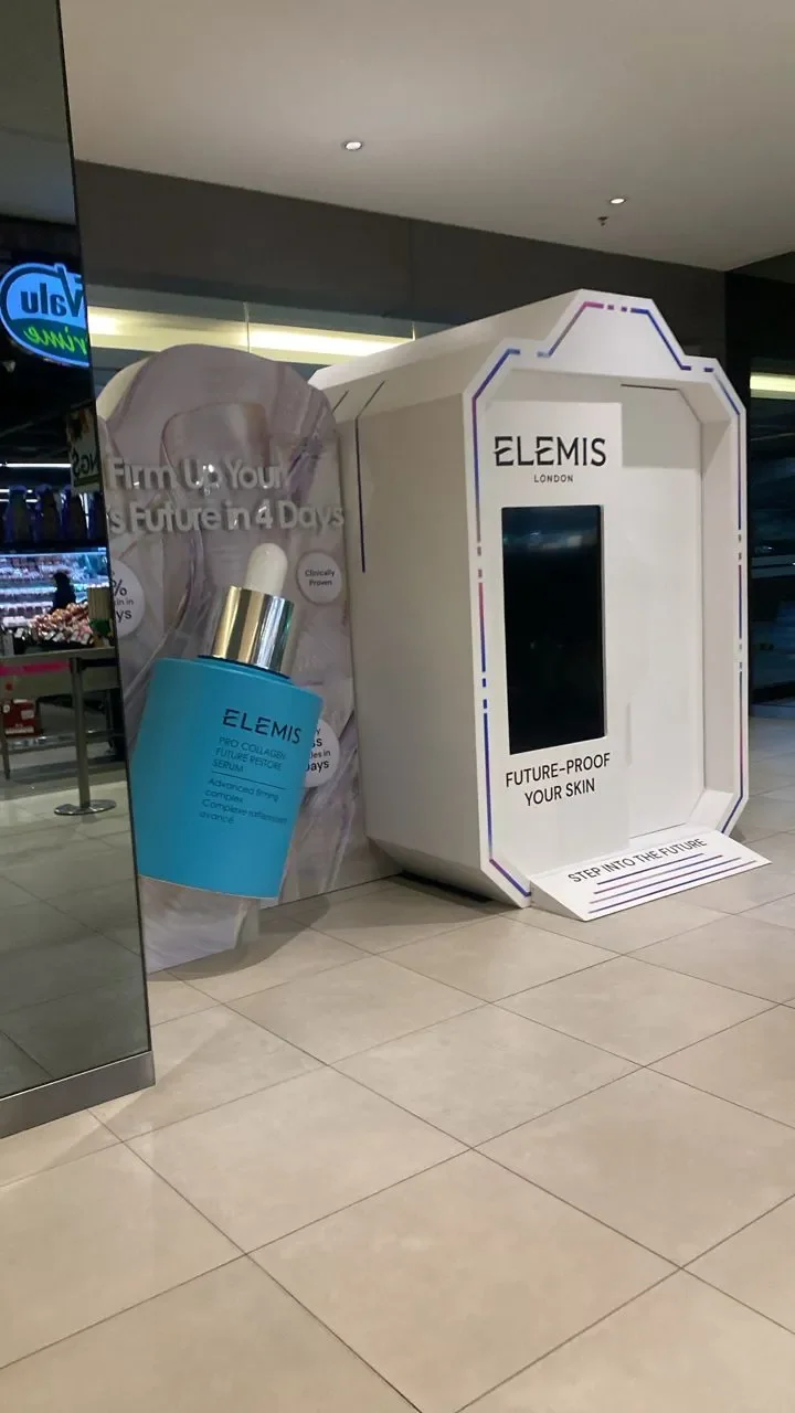 Elemis-branded enclosed photobooth and touchscreen at a shopping-centre event, side view