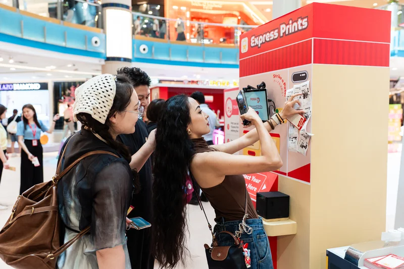 Guests taking a photo at the POKKA Express Prints receipt photobooth with printed receipts displayed beside the screen