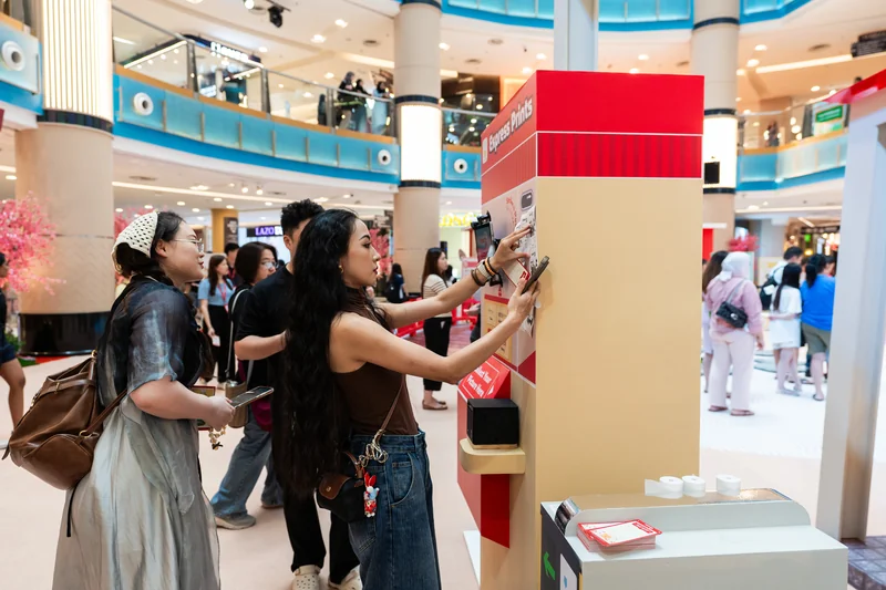 Side view of guests using the POKKA Express Prints receipt photobooth at the event