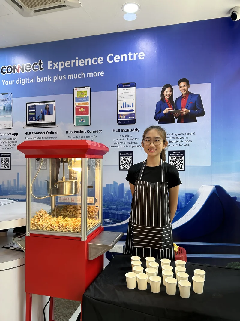 An operator with the red popcorn machine and serving cups at an HLB event