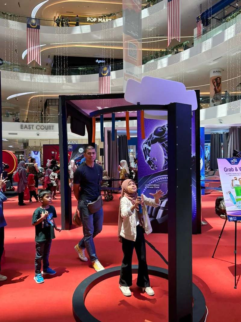 A guest catching a blue stick beneath the black overhead ring at a mall activation