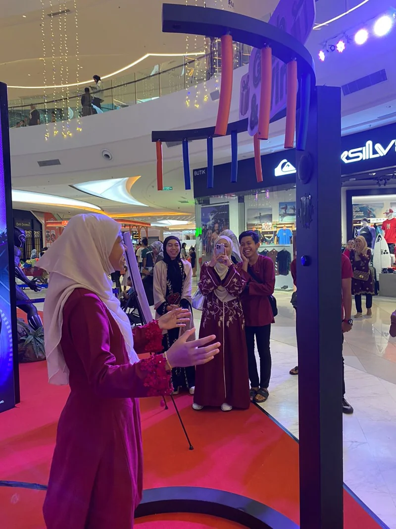 A guest reaching for falling sticks on the circular stick-catching game at a mall