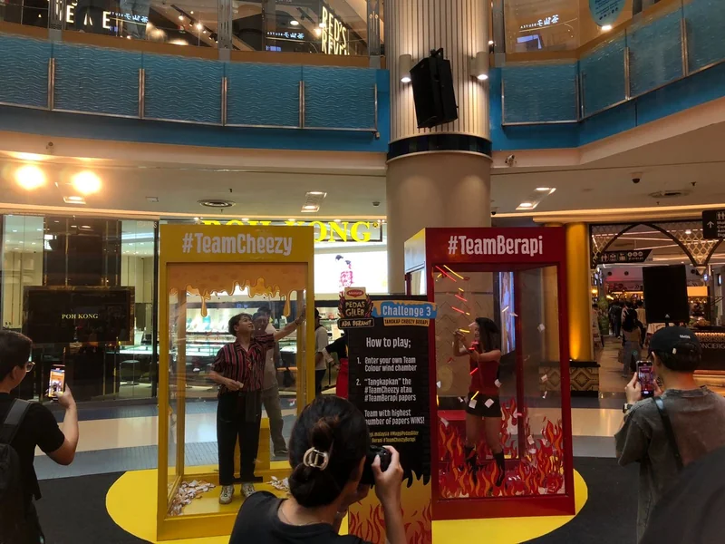 Yellow and red wind chambers with participants at a shopping-centre event